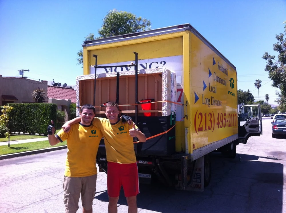 Two KF Moving movers beside their yellow moving truck