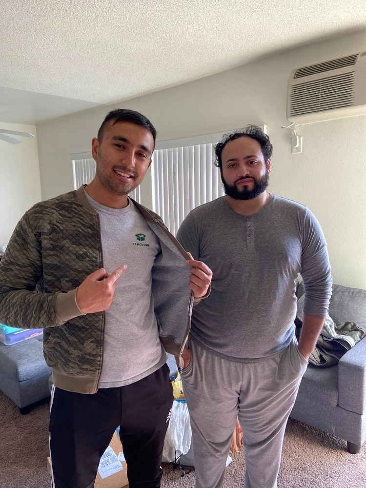 Two people posing beside a sofa on moving day