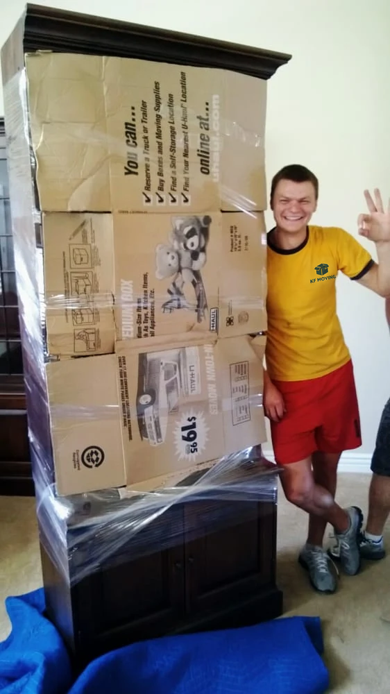 KF Moving mover beside packed and wrapped moving boxes