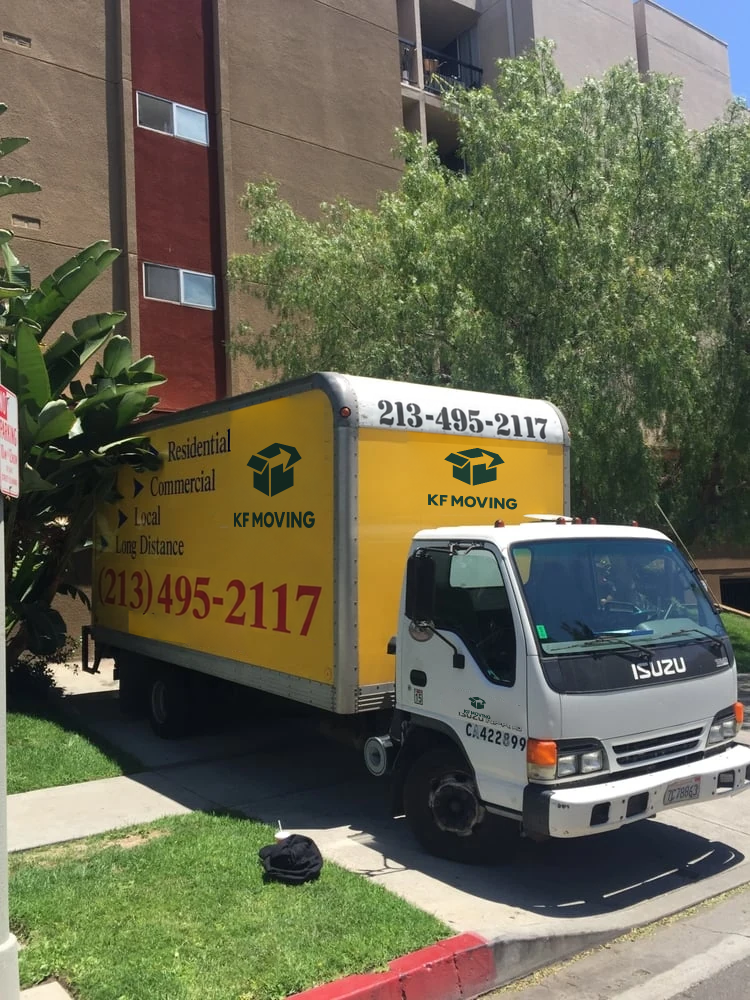 Yellow KF Moving truck parked outside a residential building